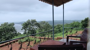Un balcón con vista al mar y las colinas, una mesa y una silla.