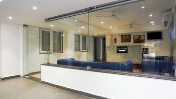 Uma área de recepção com divisória de vidro, assentos, ventilador de teto e placa indicando 'TOWNHOUSE & Company Services'.