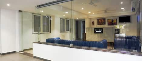 Un área de recepción con mampara de vidrio, asientos, un ventilador de techo y un cartel que indica 'TOWNHOUSE & Company Services'.