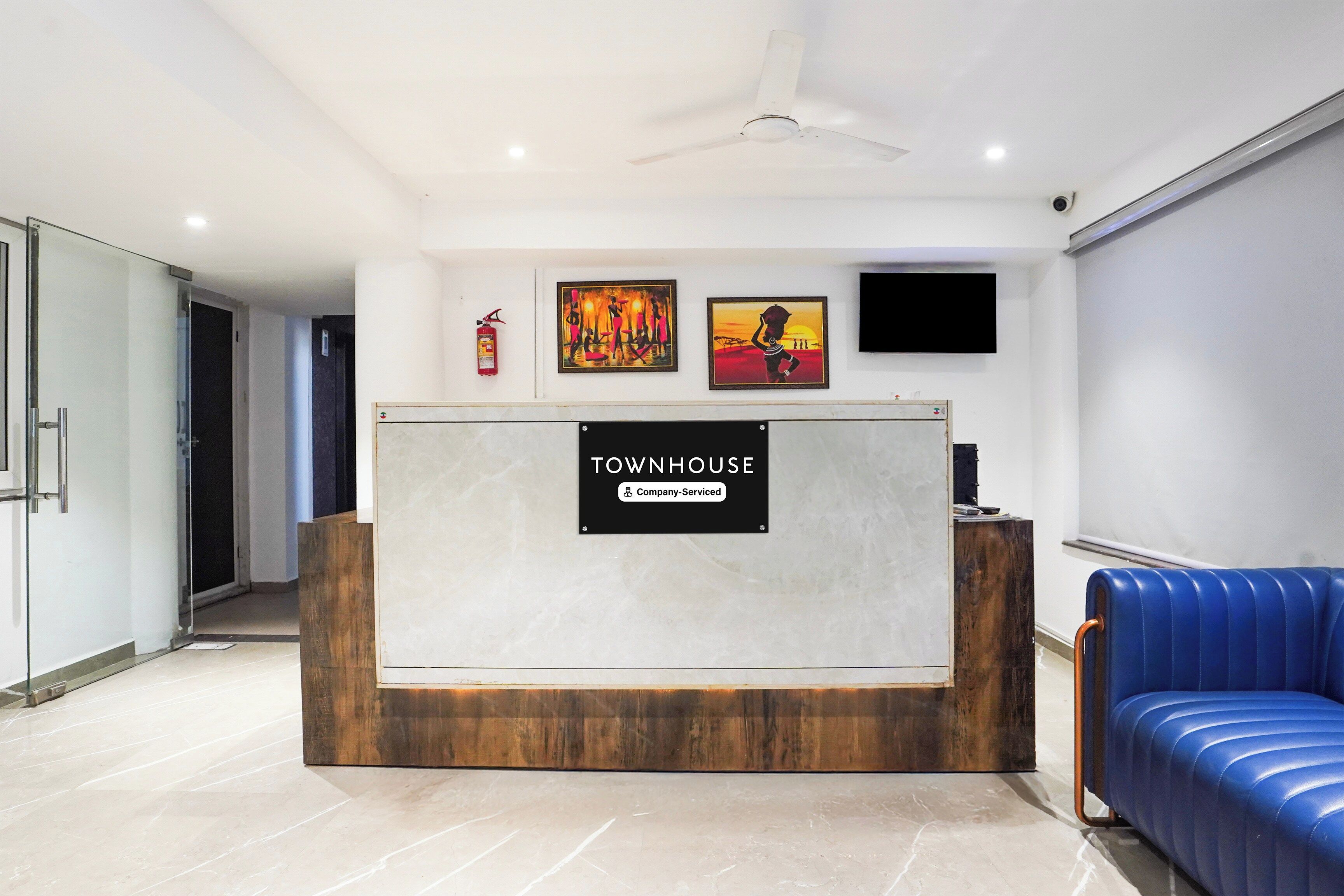 Un mostrador de recepción con un cartel que dice 'Townhouse', un extintor y una obra de arte en la pared.