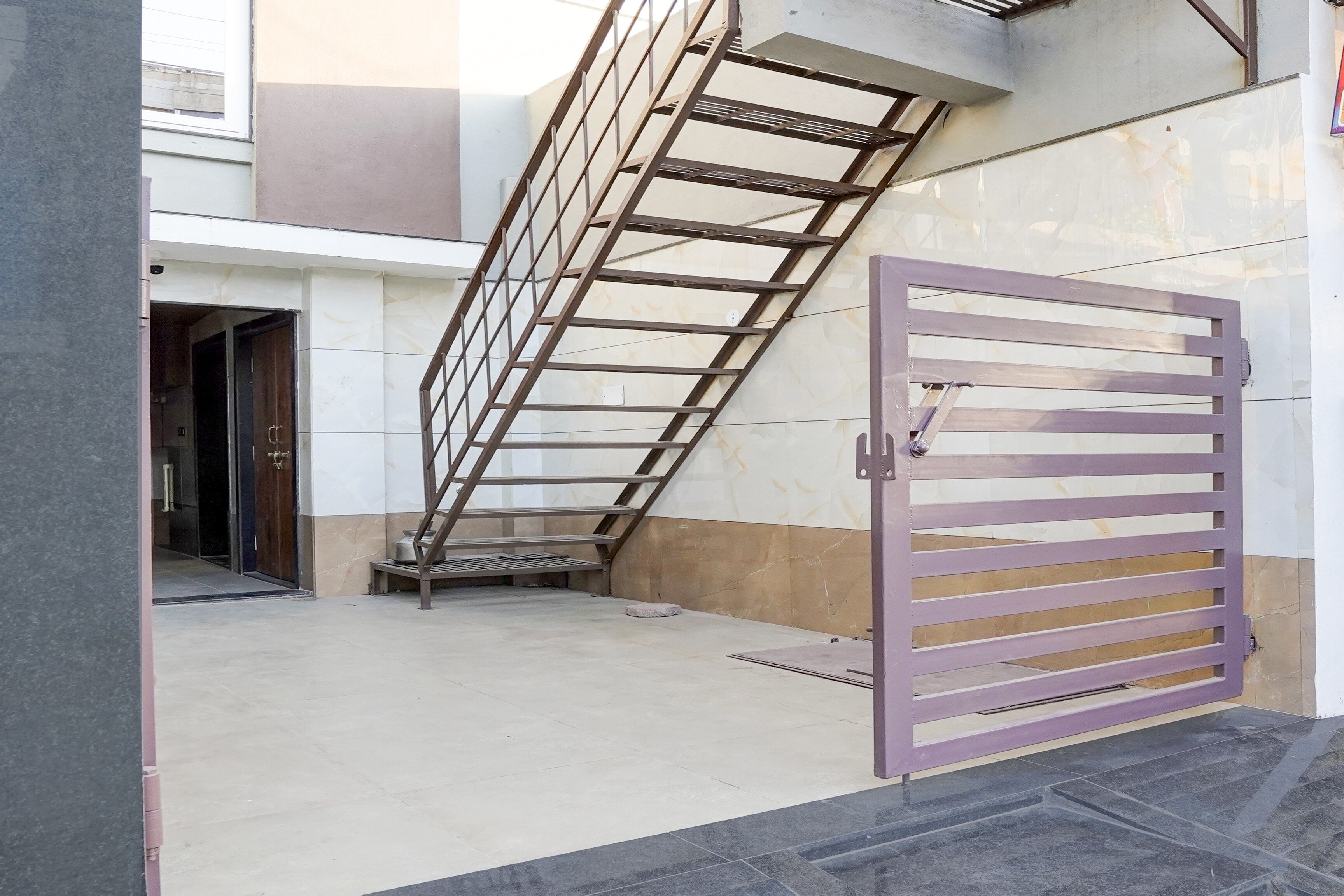 Una entrada con reja y una escalera metálica que lleva a una puerta.