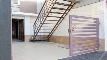 Una entrada con reja y una escalera metálica que lleva a una puerta.