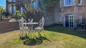 An outdoor seating area with a table and chairs, a bottle of wine, and a glass. - 1 bedroom accommodation in Whitby (Whitby)