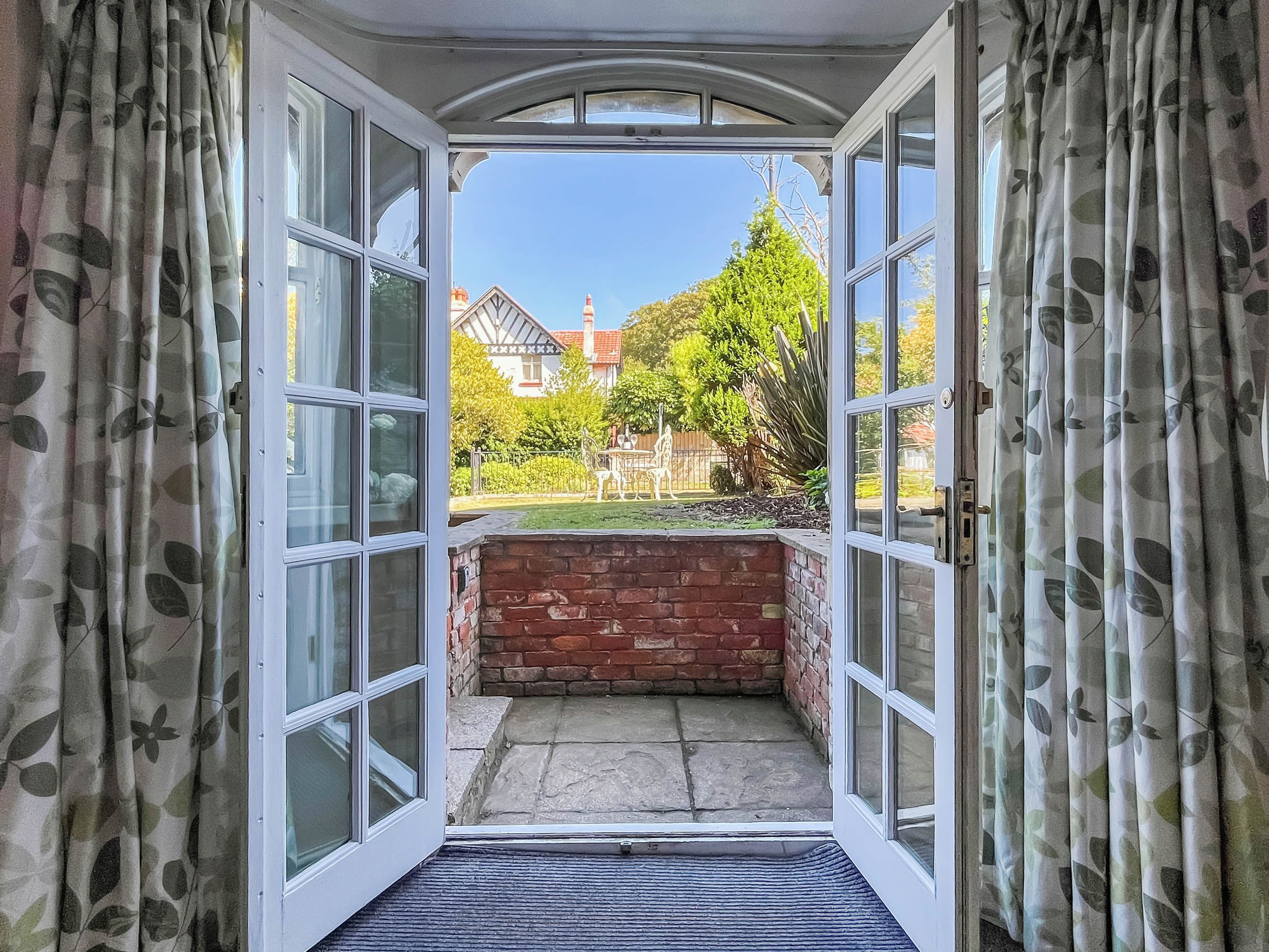 A view through a glass door with a brick wall and a clear sky.