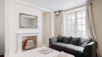 Ein Hotelzimmer mit Bett, einer Couch, einem Kamin und einem großen Fenster mit Vorhängen.