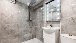 A modern bathroom with a shower, toilet, and sink. - 1 bedroom accommodation in Whitby (Whitby)