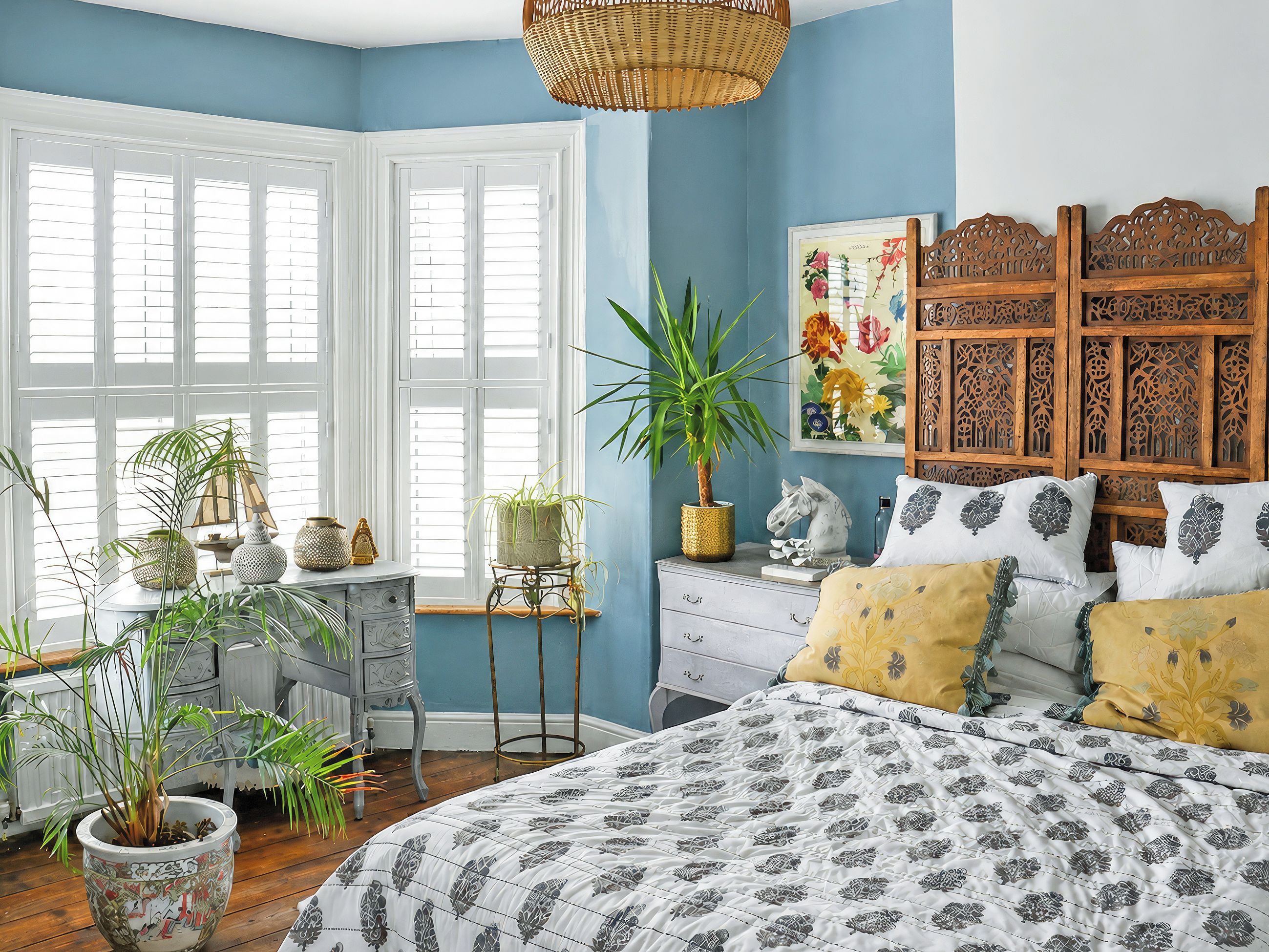 A bedroom with a large bed, a dresser, a window with shutters, and a wall-mounted wooden headboard.