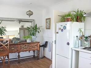A kitchen with a wooden table, a white refrigerator, and various potted plants. - 3 bedroom accommodation in Reydon, Southwold (Reydon, Southwold)