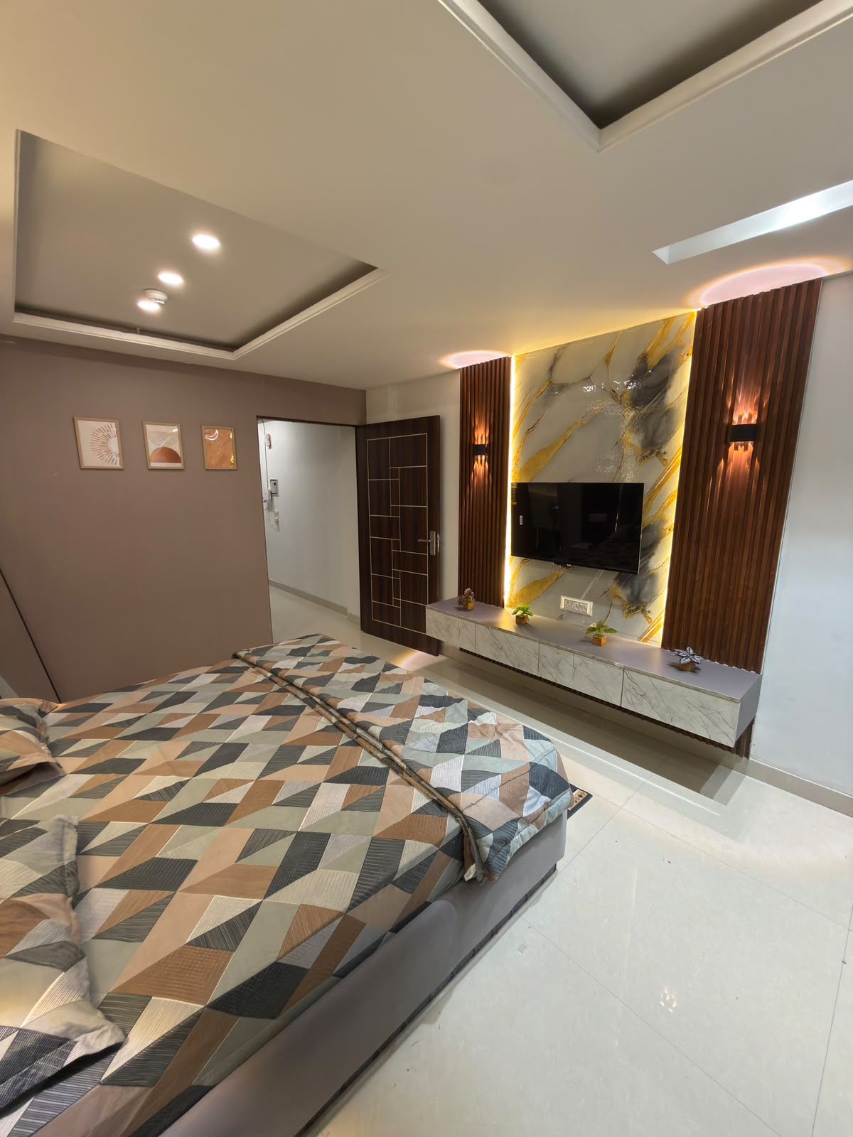 A modern bedroom with a bed, a TV mounted on the wall, and a decorative wall panel.
