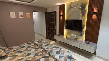 A modern bedroom with a bed, a TV mounted on the wall, and a decorative wall panel.