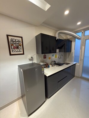 A compact kitchen with a built-in refrigerator, a sink, and a window.