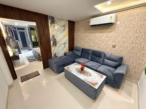 A modern living room with a sectional sofa, a coffee table, and a patterned wall.