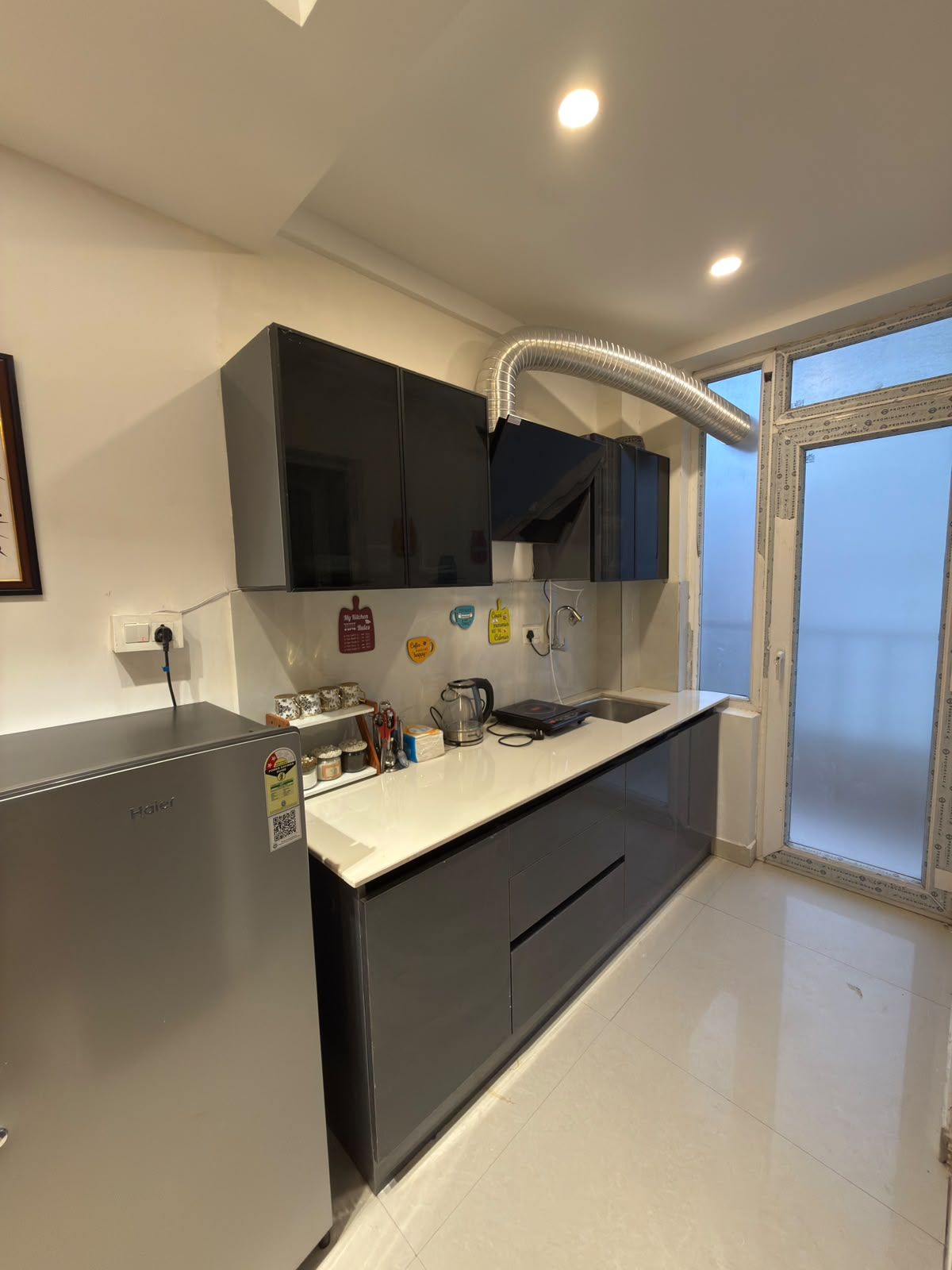 Eine moderne Küche mit einem Einbaukühlschrank, einer Spüle und einem Fenster mit Blick auf einen Balkon.
