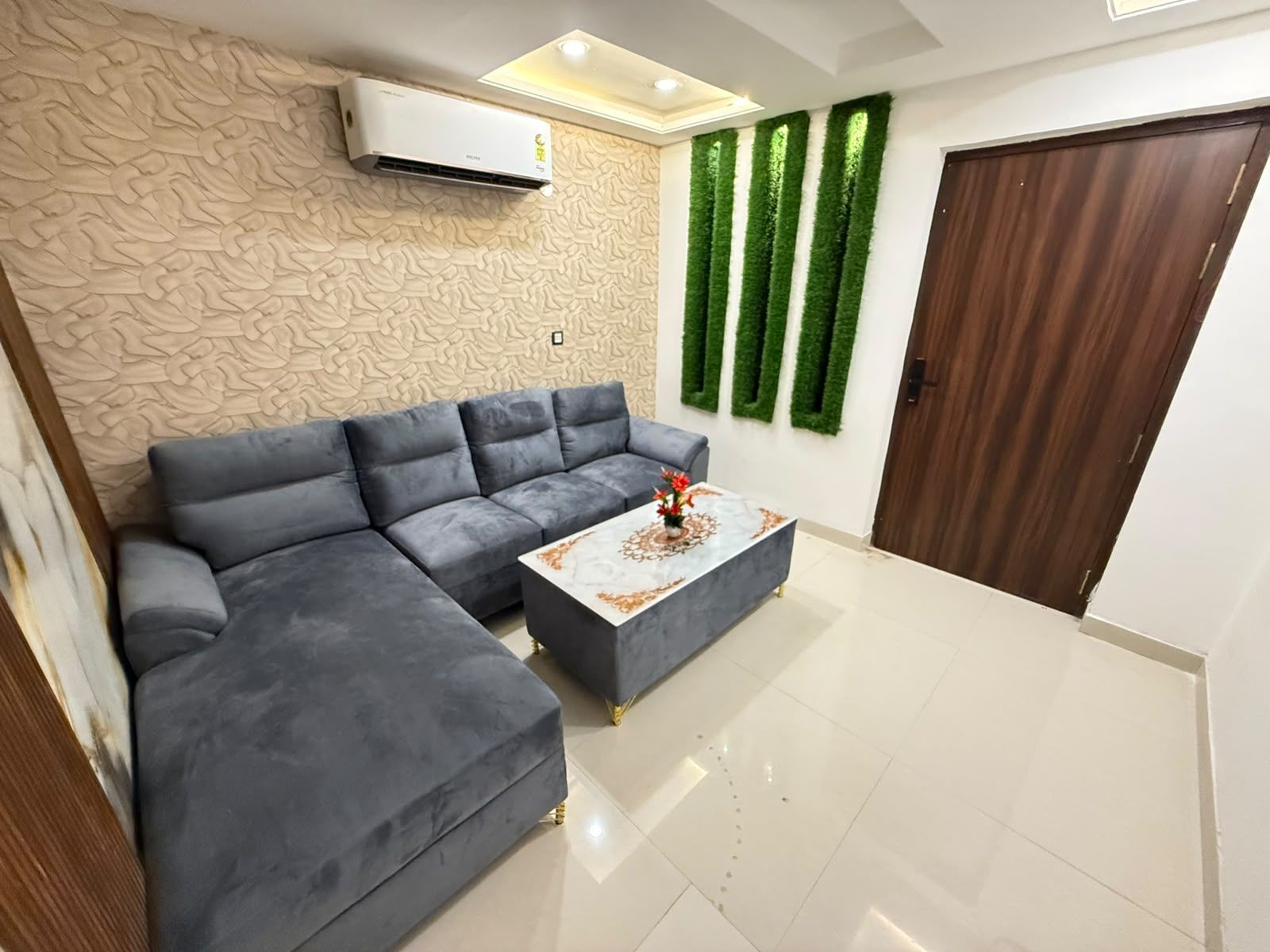 A modern living room with a sectional sofa, a coffee table, and decorative green vertical elements on the wall.