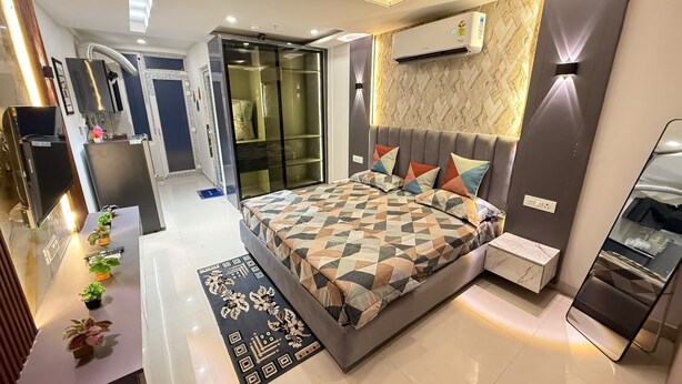Quarto moderno com cama, mesas de cabeceira, ar condicionado e banheiro com espelho.