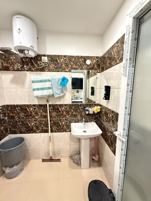 Un baño con lavamanos blanco, espejo, toallero, inodoro y zona de ducha.