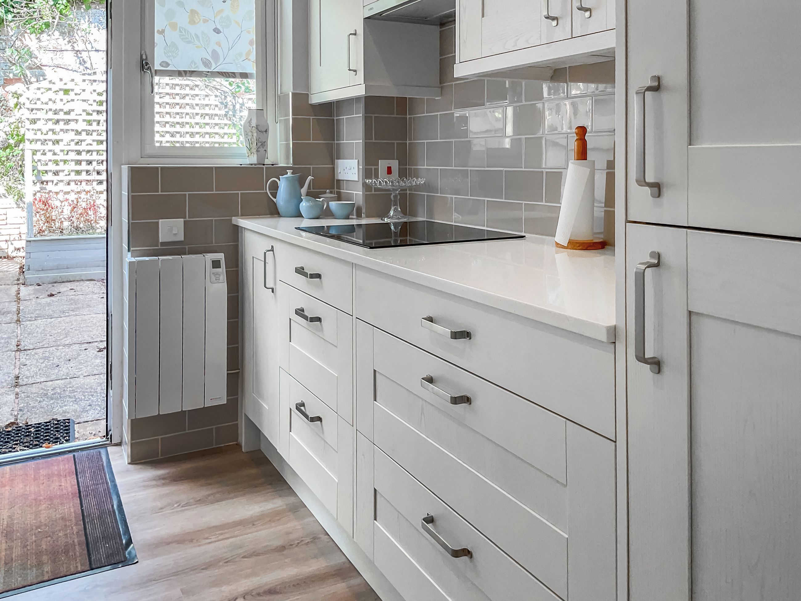 A modern kitchen with white cabinetry, a built-in oven, and a window with a view of the outside.