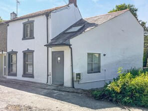 A two-story house with a grey door, two windows with shutters, and a small porch area. - 2 bedroom accommodation in St Columb Major (St Columb Major)