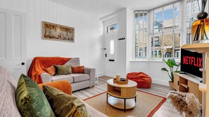 A modern living room with a sofa, a coffee table, and a television displaying 'NETFLIX'. - A terraced cottage on Bennett Street, in the heart of Buxton. (Buxton)