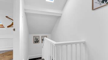 A staircase with a white railing, a skylight, and two framed botanical prints on the wall.