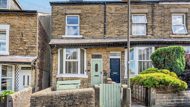 A two-story stone house with a green door, a small porch, and a neatly trimmed hedge. - A terraced cottage on Bennett Street, in the heart of Buxton. (Buxton)