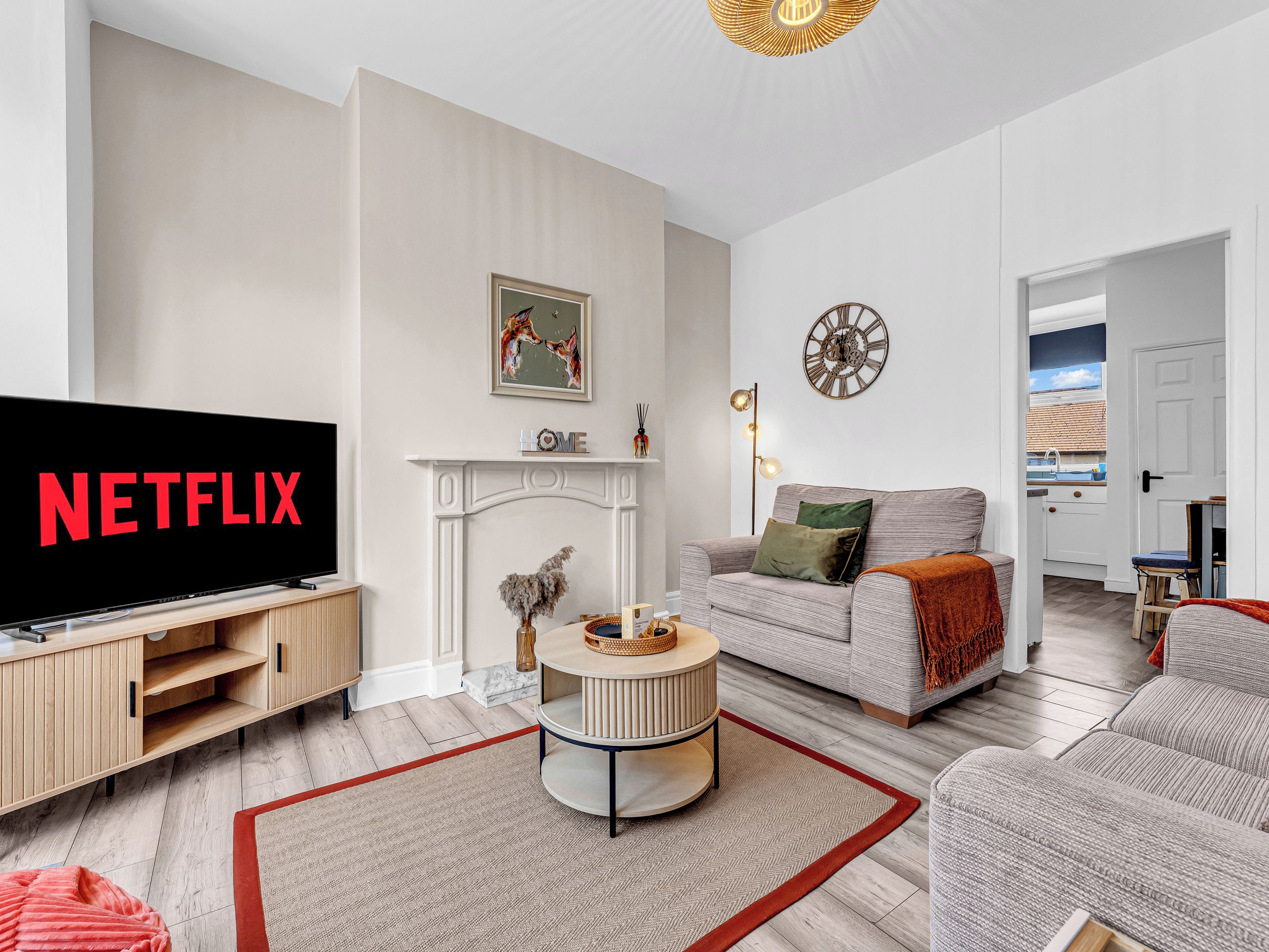 A modern living room with a television displaying 'NETFLIX,' a fireplace, a sofa, and a dining area with a view.