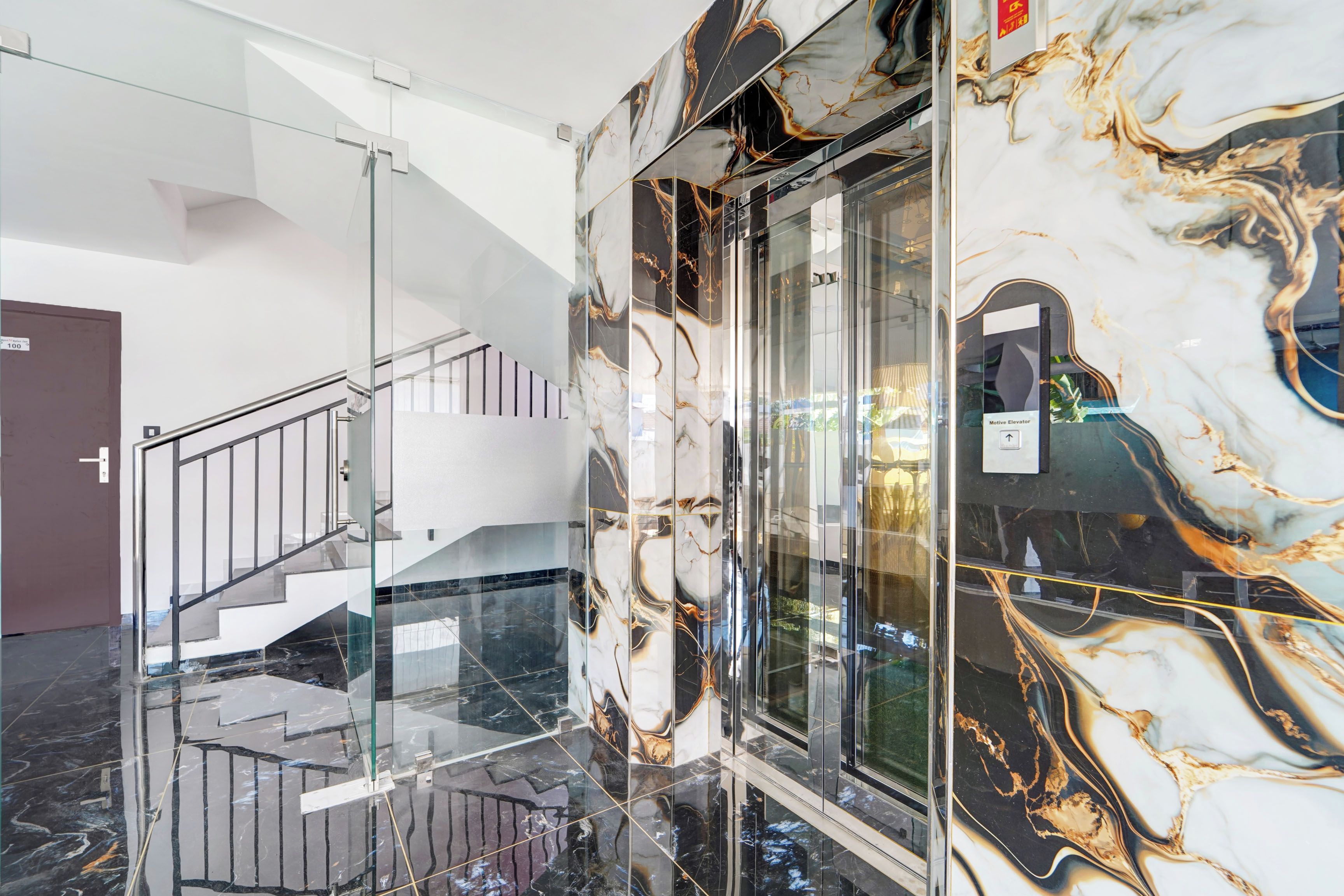 A modern elevator with marble walls and a glass enclosure.