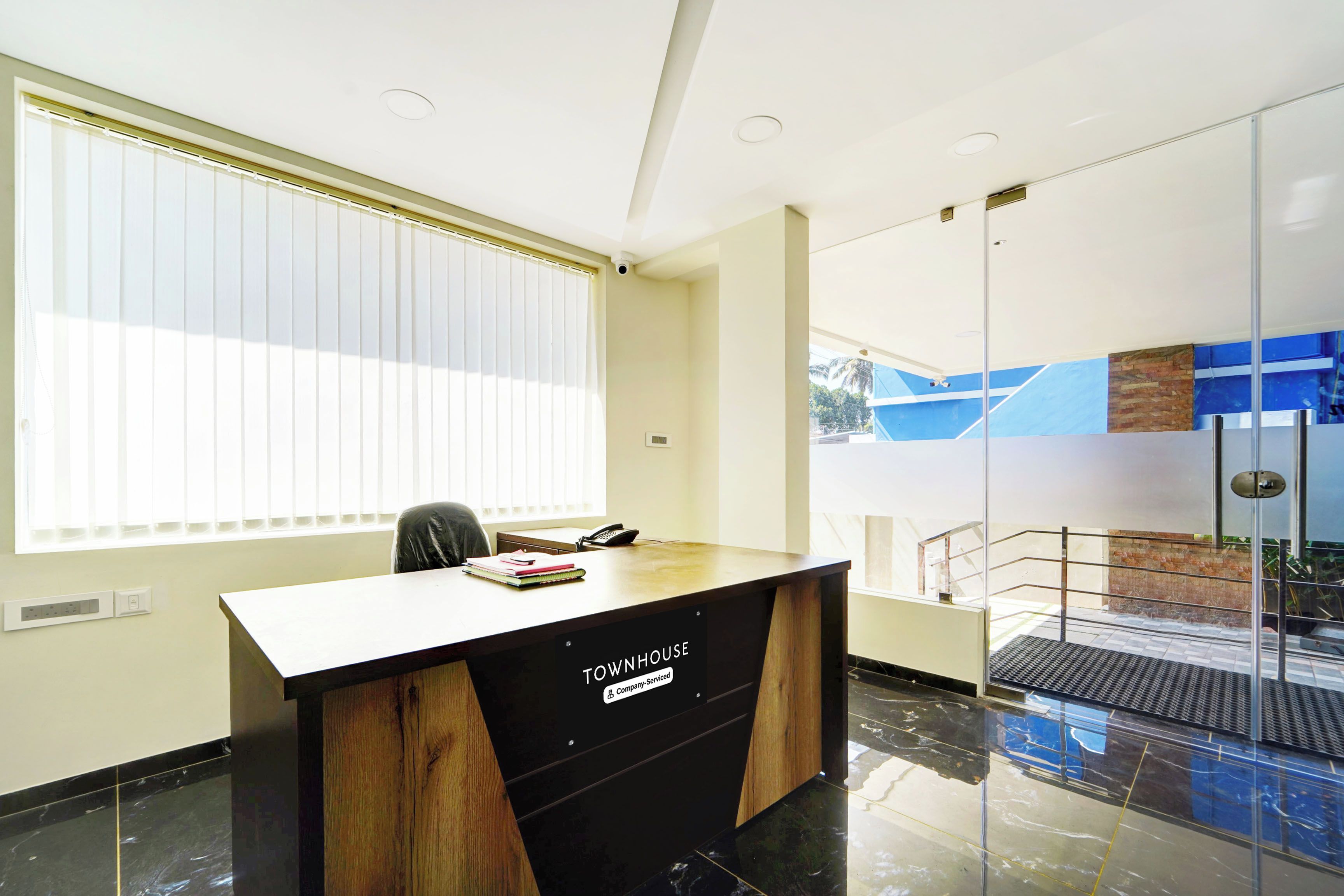 A modern office space with a wooden desk, a chair, and a window with blinds.