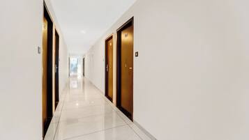 Un pasillo con puertas a ambos lados, que conduce a una habitación luminosa al final.
