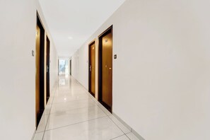 A corridor with doors on both sides, leading to a bright room at the end.