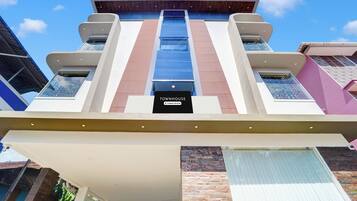 A modern building with a central staircase, multiple balconies, and a sign reading 'TOWNHOUSE Company-Served'.