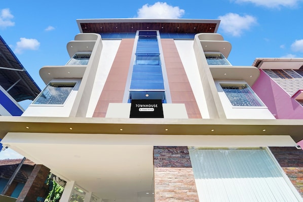 A modern building with a central staircase, multiple balconies, and a sign reading 'TOWNHOUSE Company-Served'.