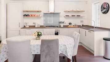 Une cuisine moderne avec des meubles blancs, un îlot central et un coin repas comprenant une table ronde et des chaises.