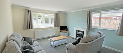 A living room with two sofas, a coffee table, a fireplace, and a television.