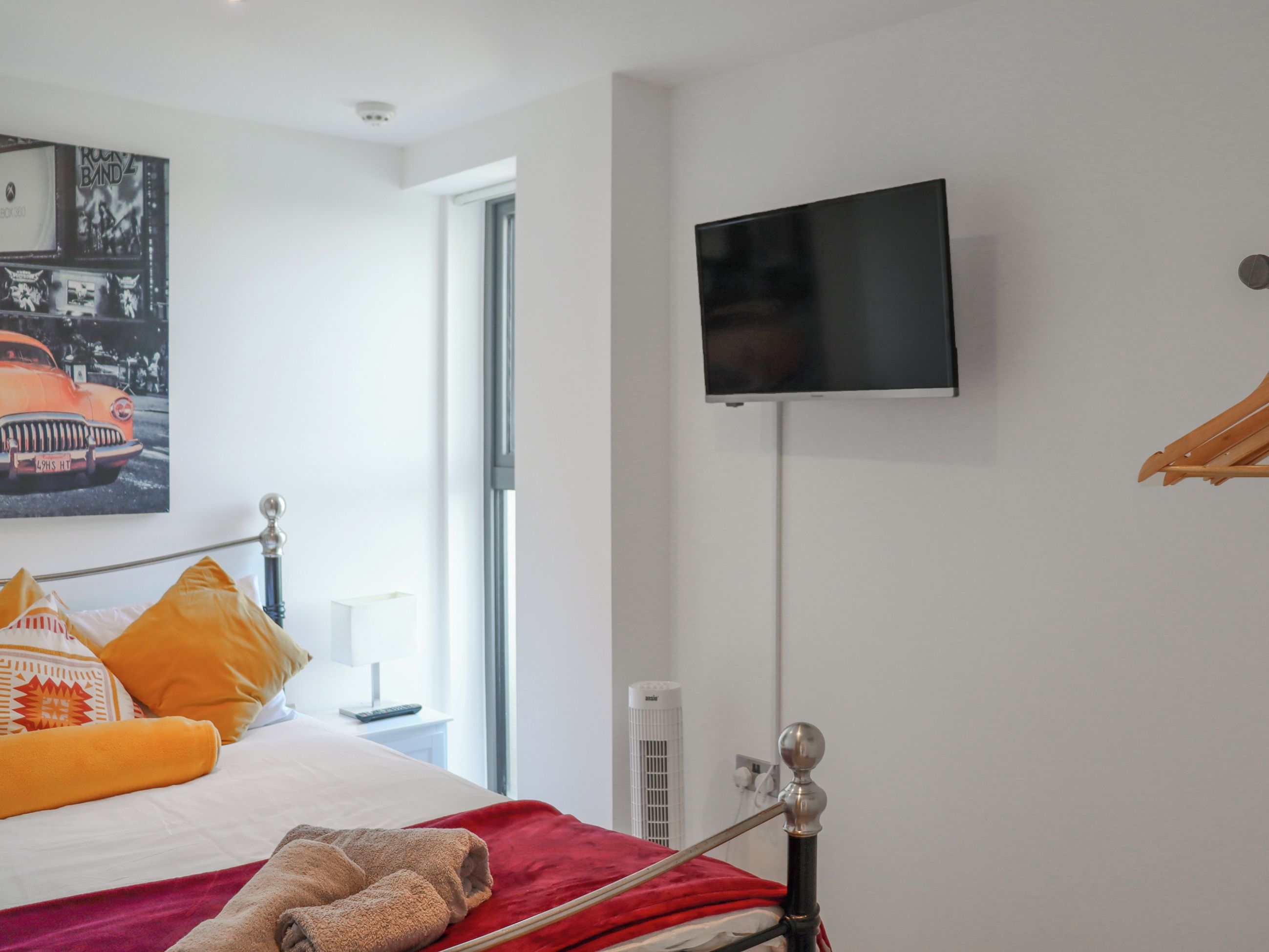 A hotel room with a bed, a TV mounted on the wall, and a window.
