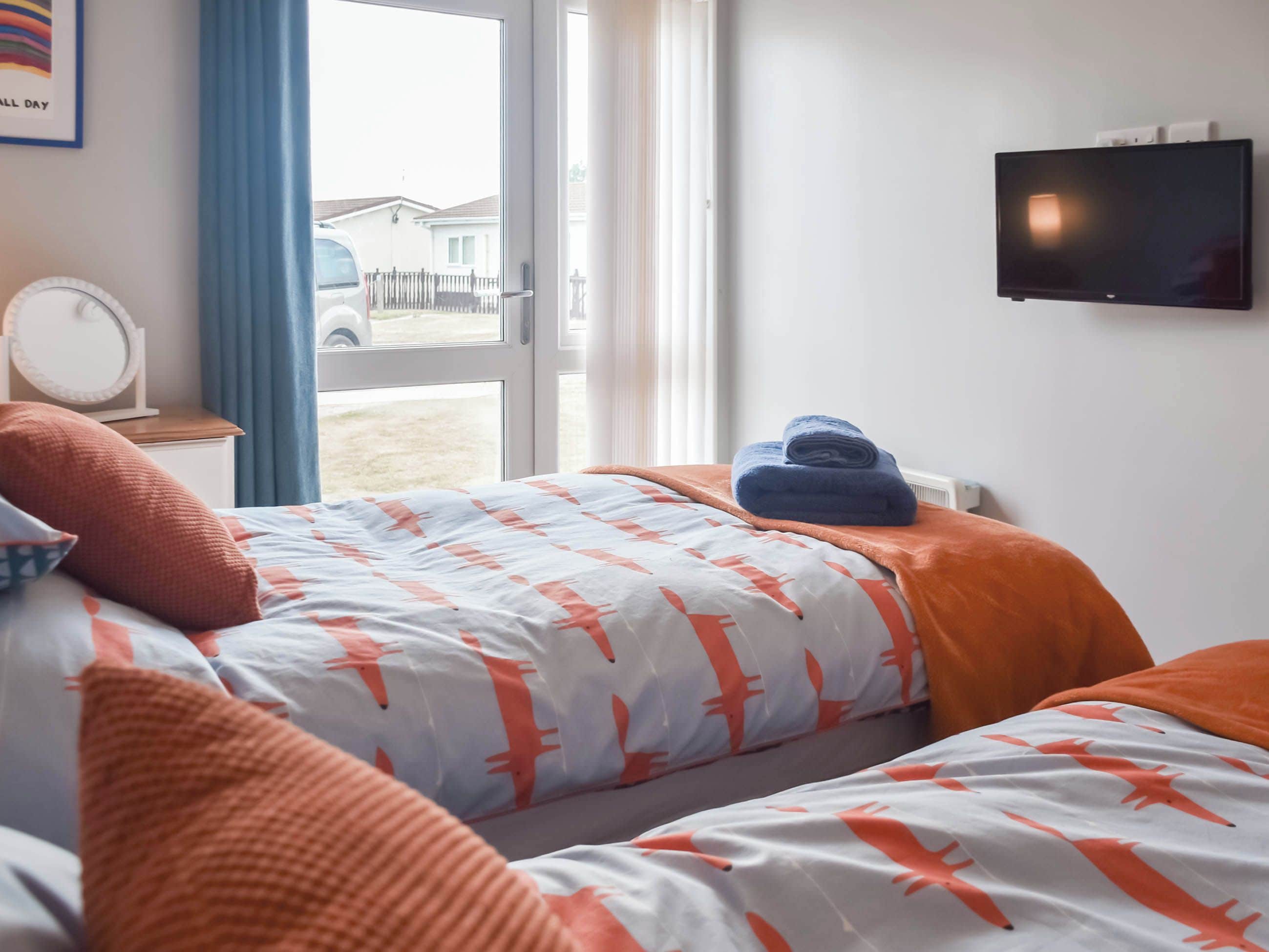 A hotel room with a bed, a TV, a window, and a view of the outside.
