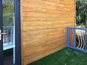 A wooden wall with horizontal planks, a glass door, and a blue metal railing. - Crosspark Bungalow Stables (Ashburton)