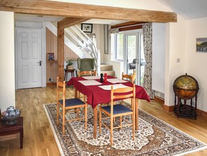 A dining area with a wooden table, chairs, and a red tablecloth. There is a globe on a stand and a patterned rug on the floor. - Crosspark Bungalow Stables (Ashburton)