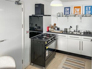 Ett modernt kök med en gasspis, ugn och en inbyggd diskmaskin.