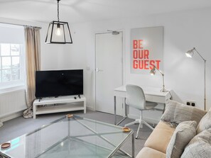 A modern living room with a glass coffee table, a flat-screen TV, a desk, and a couch. - 1 bedroom accommodation in Bridlington (Bridlington)