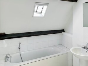 Ein Badezimmer mit einer Badewanne, einer Dusche, einem Fenster und einem Waschbecken.