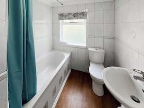 Et badeværelse med badekar, toilet og håndvask.