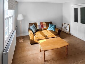 En stue med sofa, sofabord, gulvlampe og radiator.