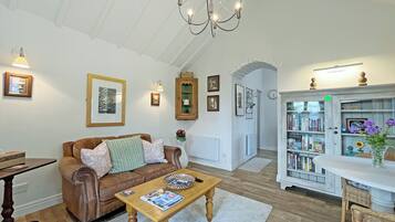 En stue med en brun lædersofa, et træbord og en lysekrone.