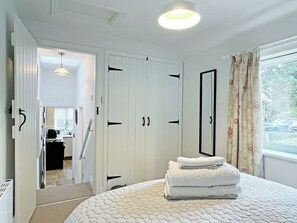 A bedroom with a bed, a wardrobe, a mirror, and a window with curtains.