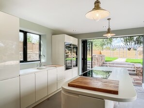 A modern kitchen with a large island, built-in appliances, and a view of the backyard. - Lower Tower Hill Farm (Up Holland, West Lancashire)