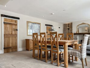 A dining area with a wooden table and chairs, a stone wall, and a fireplace. - Lower Tower Hill Farm (Up Holland, West Lancashire)