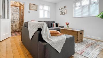 A living room with a grey sofa, a wooden coffee table, and a patterned rug.