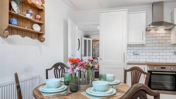 A dining area with a round table set for four, surrounded by wooden chairs.