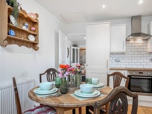 Een eetruimte met een ronde tafel voor vier personen, omringd door houten stoelen.